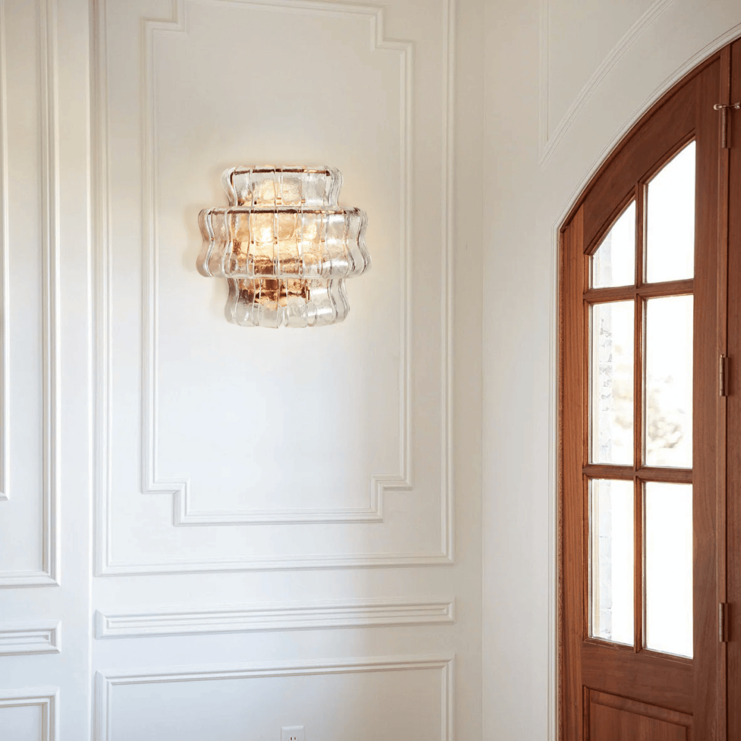 Decorative wall sconce on a white paneled wall with a wooden door.