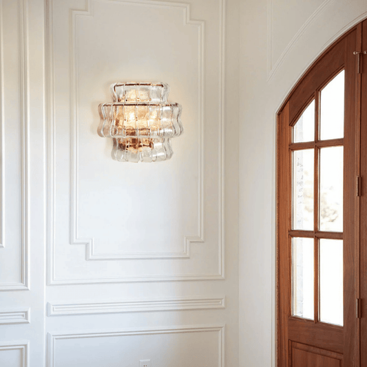 Decorative wall sconce on a white paneled wall with a wooden door.