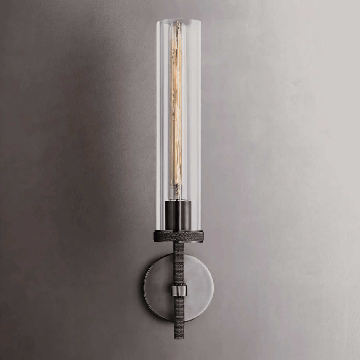 Modern wall sconce with clear glass shade on a gray wall