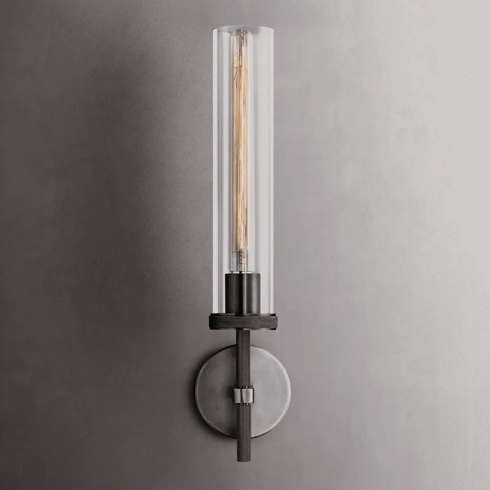 Modern wall sconce with clear glass shade on a gray wall