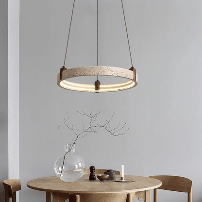 Modern pendant light hanging above a dining table with a vase and candle on a neutral background