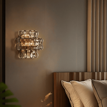 Decorative wall light fixture on a wall above a bed with pillows.