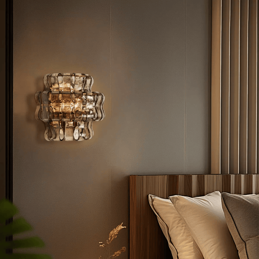 Decorative wall light fixture on a wall above a bed with pillows.