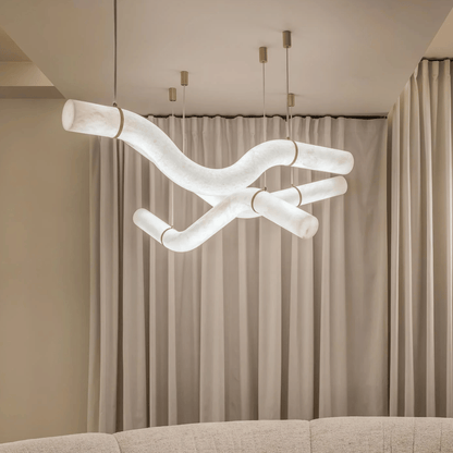Modern chandelier hanging above a sofa with beige curtains in the background