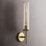 Wall-mounted light fixture with brass finish and clear glass on a gray wall.