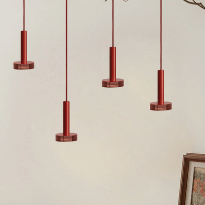 Four red pendant lights hanging against a beige wall with a framed picture on the right.