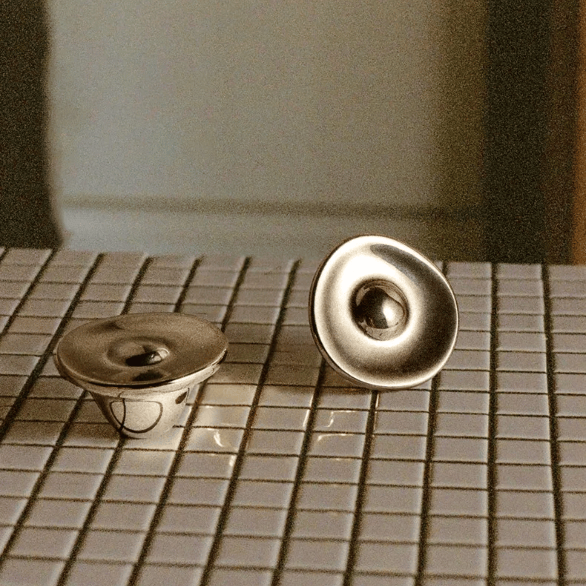 Two metallic circular objects on a tiled surface