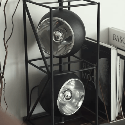 Black metal shelf with two round black objects on a white surface