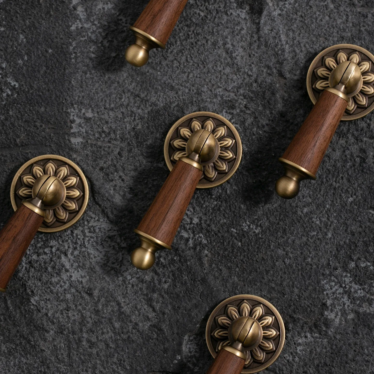Wooden handles with brass decorative elements on a dark stone surface