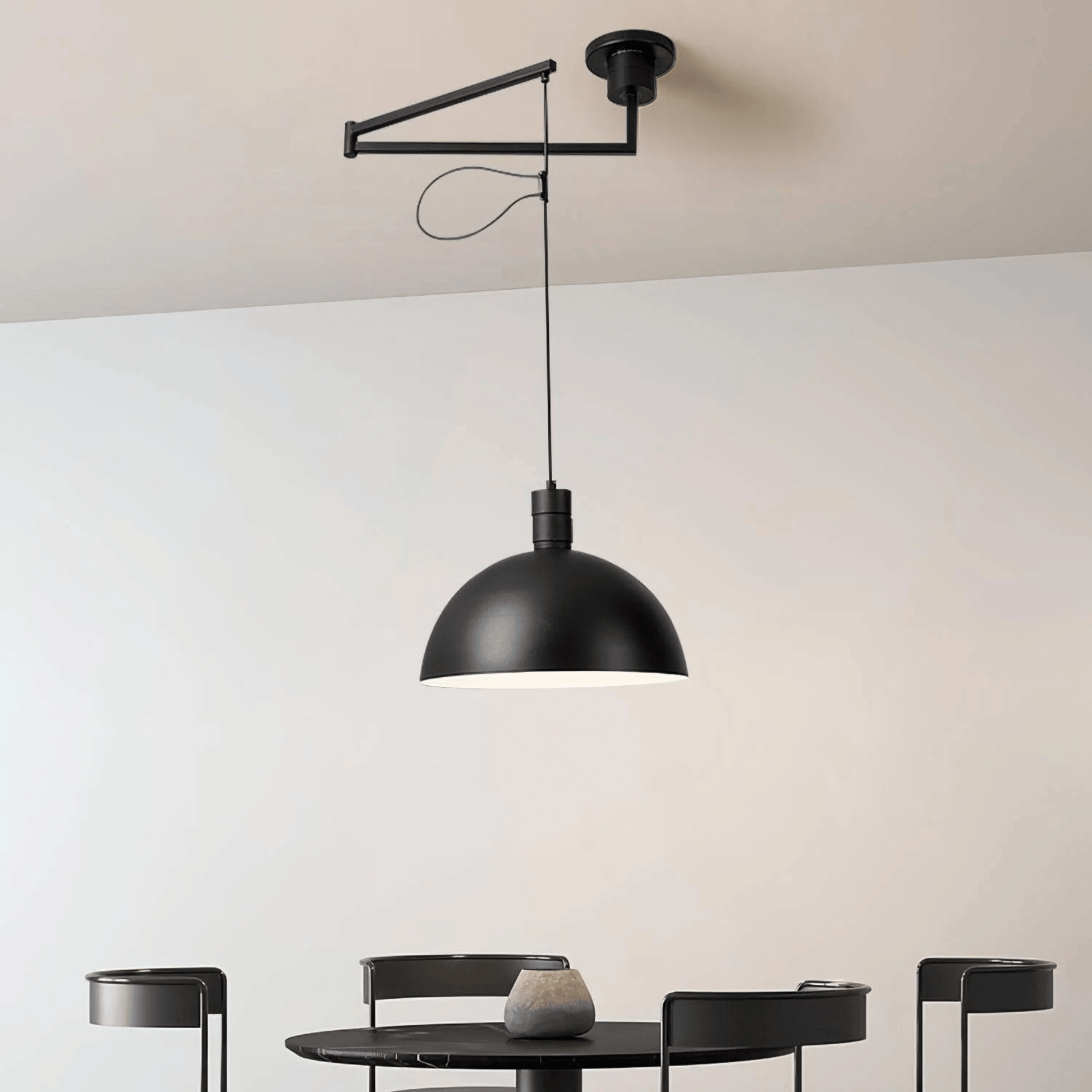 Black pendant light hanging above a dining table with a neutral background