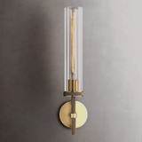 Modern wall sconce with clear glass shade and brass finish on a gray wall.