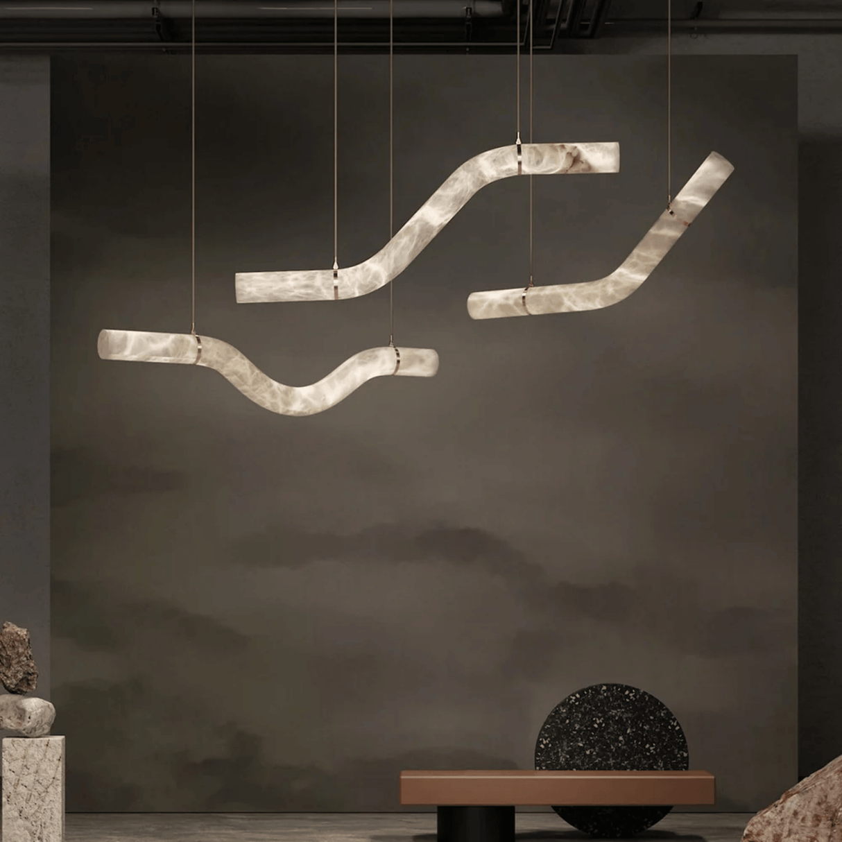 Modern pendant light fixture hanging against a dark wall with minimal decor.