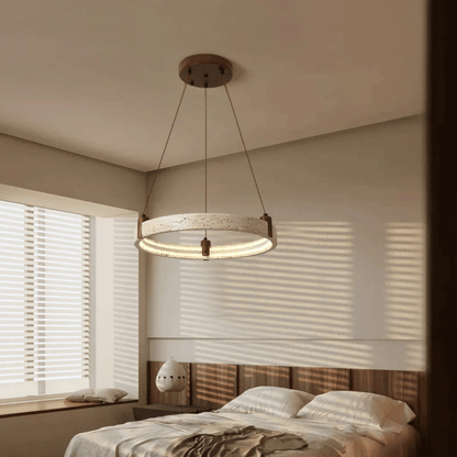 Modern pendant light hanging above a bed in a bedroom with neutral tones.