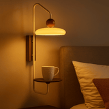 Wall-mounted lamp with a cup on a shelf in a cozy room.
