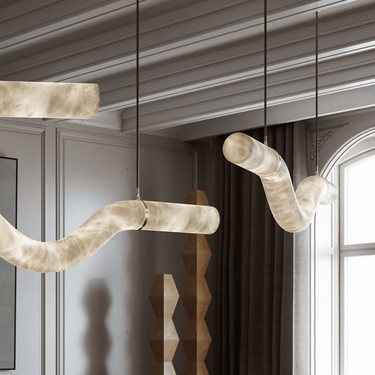 Modern pendant lights hanging in a room with gray walls and a window.