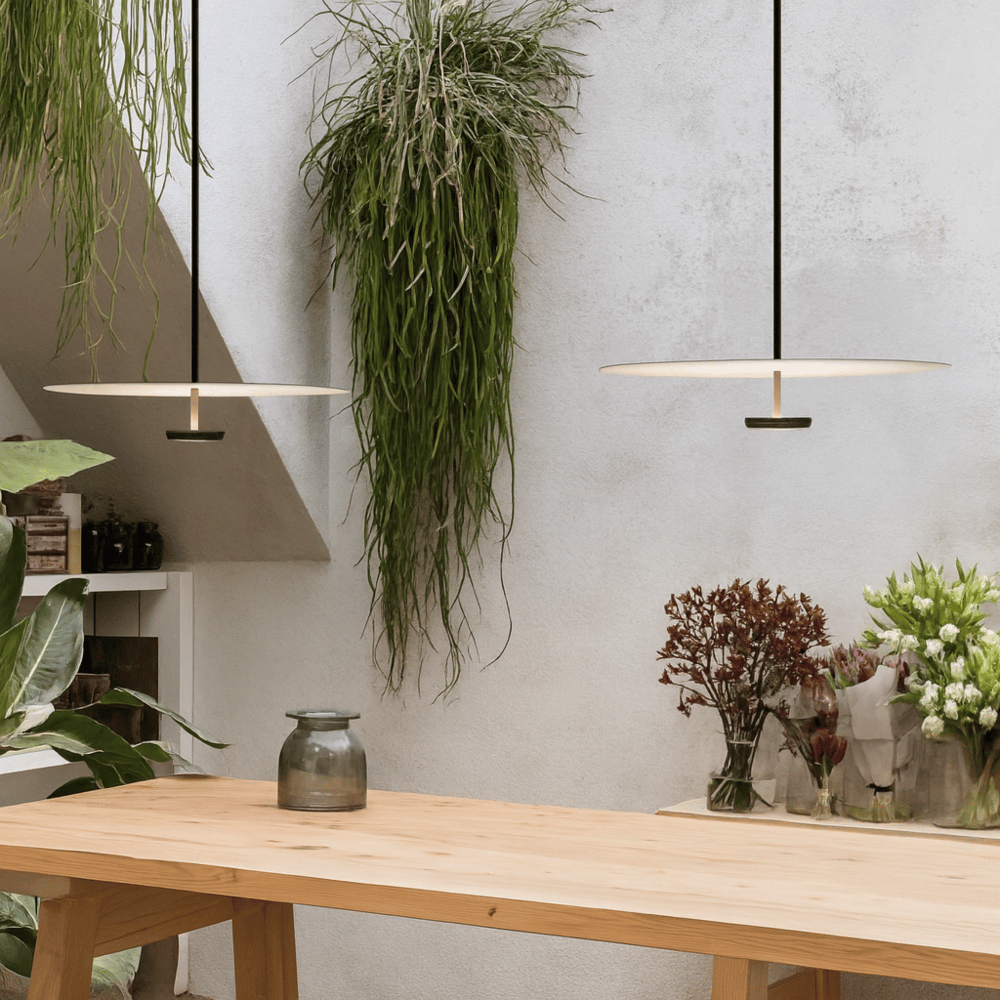 Modern interior with a wooden table, pendant lights, and decorative plants.