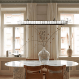Dining room with marble table, wooden chairs, and large windows.
