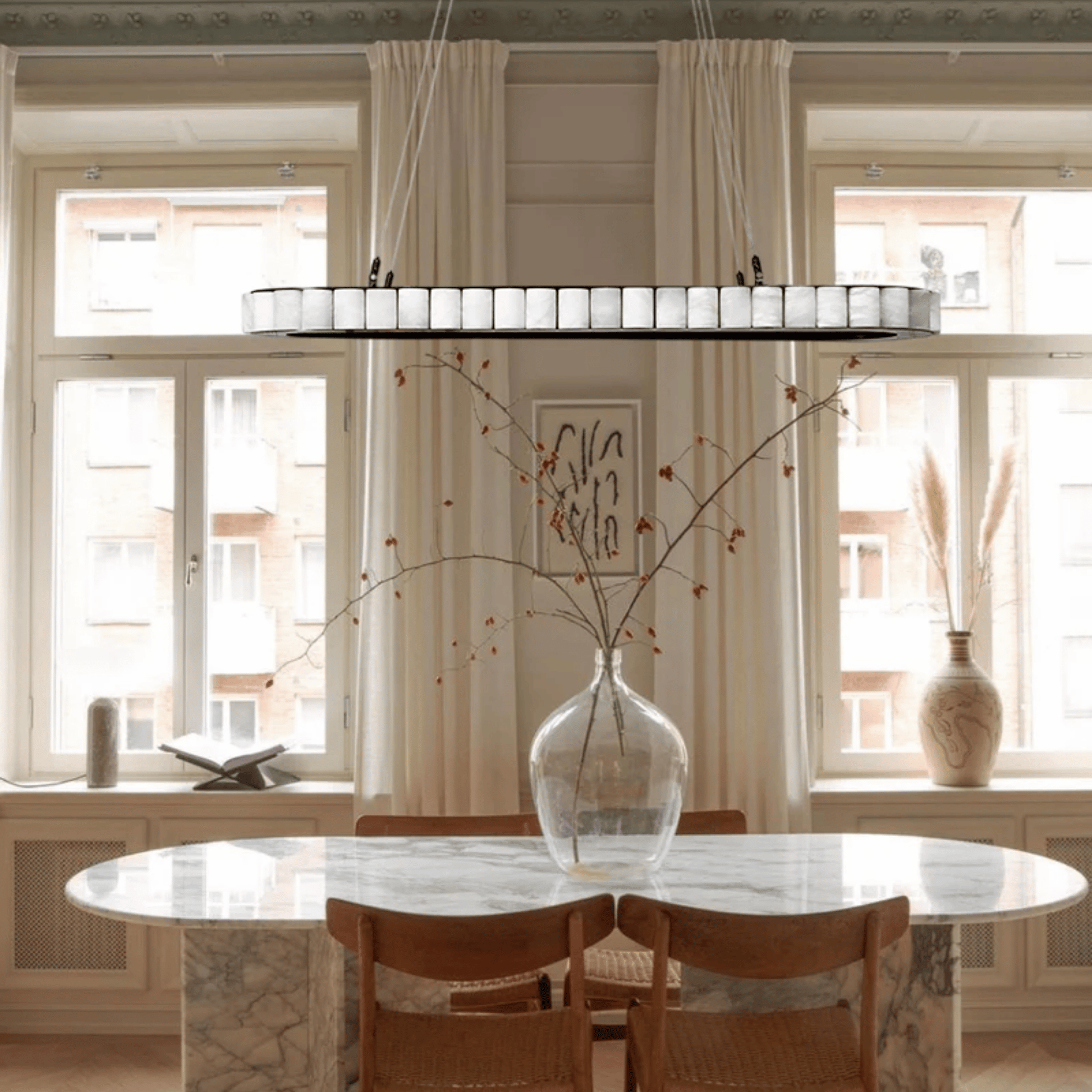 Dining room with marble table, wooden chairs, and large windows.