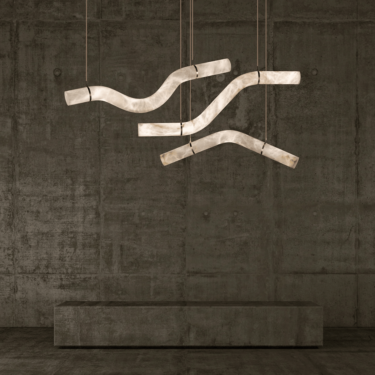 Modern chandelier with curved design hanging against a textured wall.