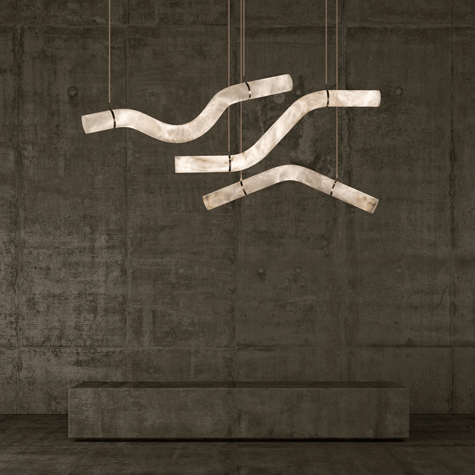 Modern chandelier with curved design hanging against a textured wall.