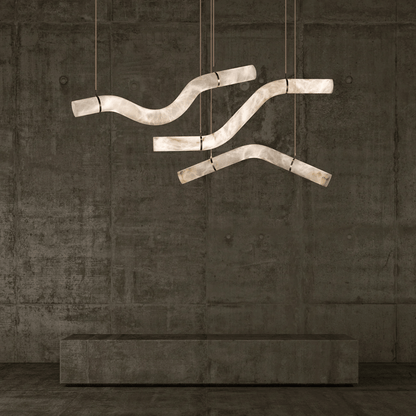 Modern chandelier with curved design hanging against a textured wall.