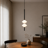 Modern pendant light hanging above a wooden table in a room with neutral decor.