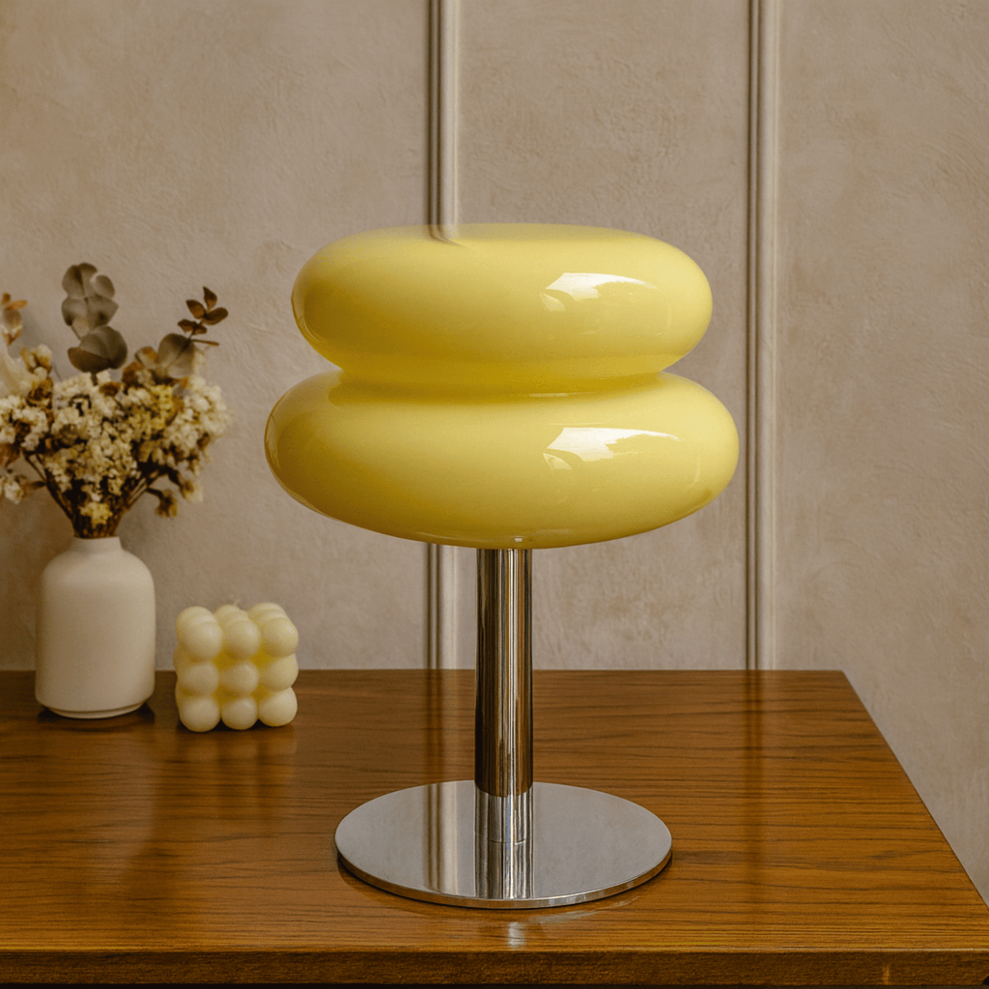 Yellow stool with a metallic base on a wooden surface, with decorative items in the background.