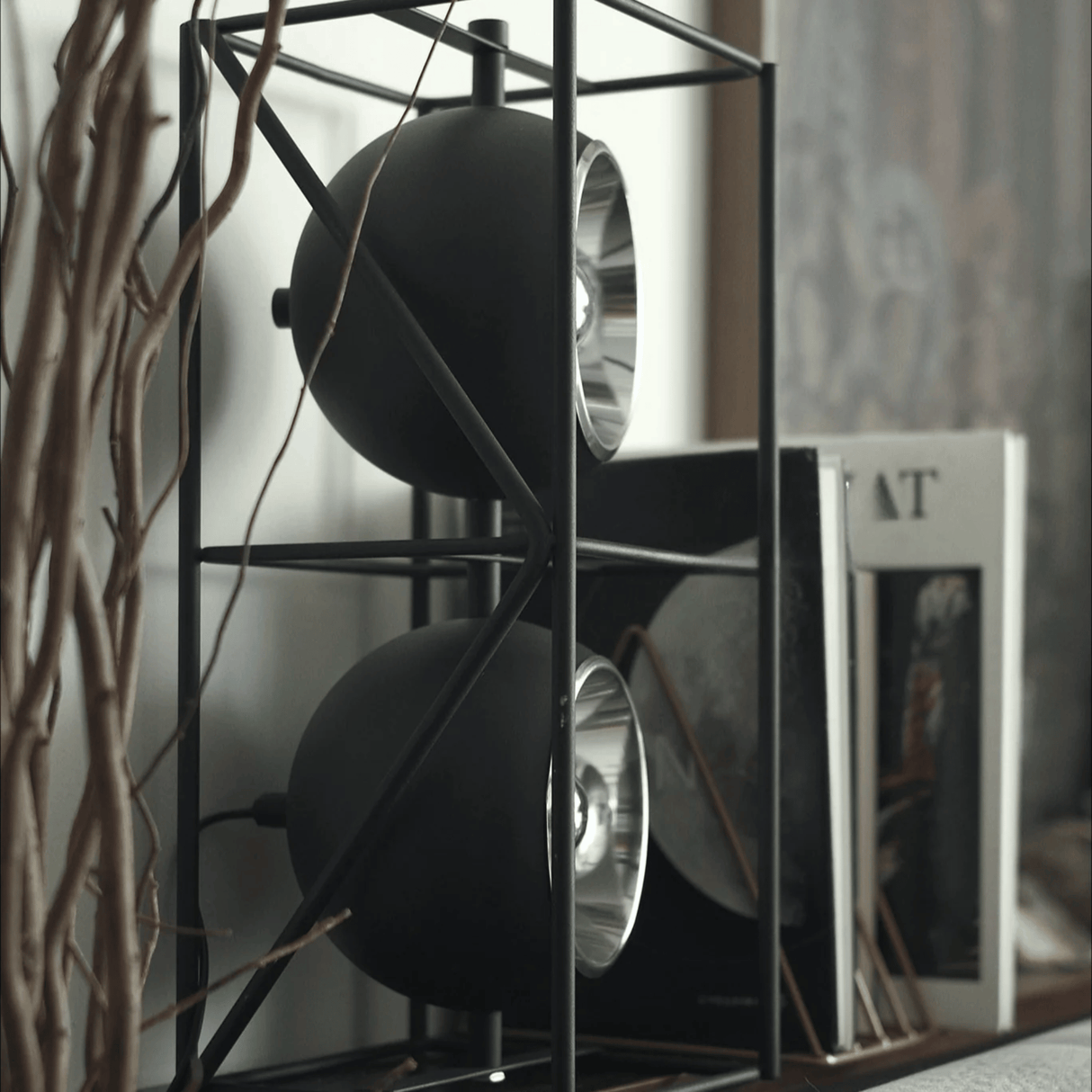 Decorative shelf with black spherical objects and books in a blurred indoor setting