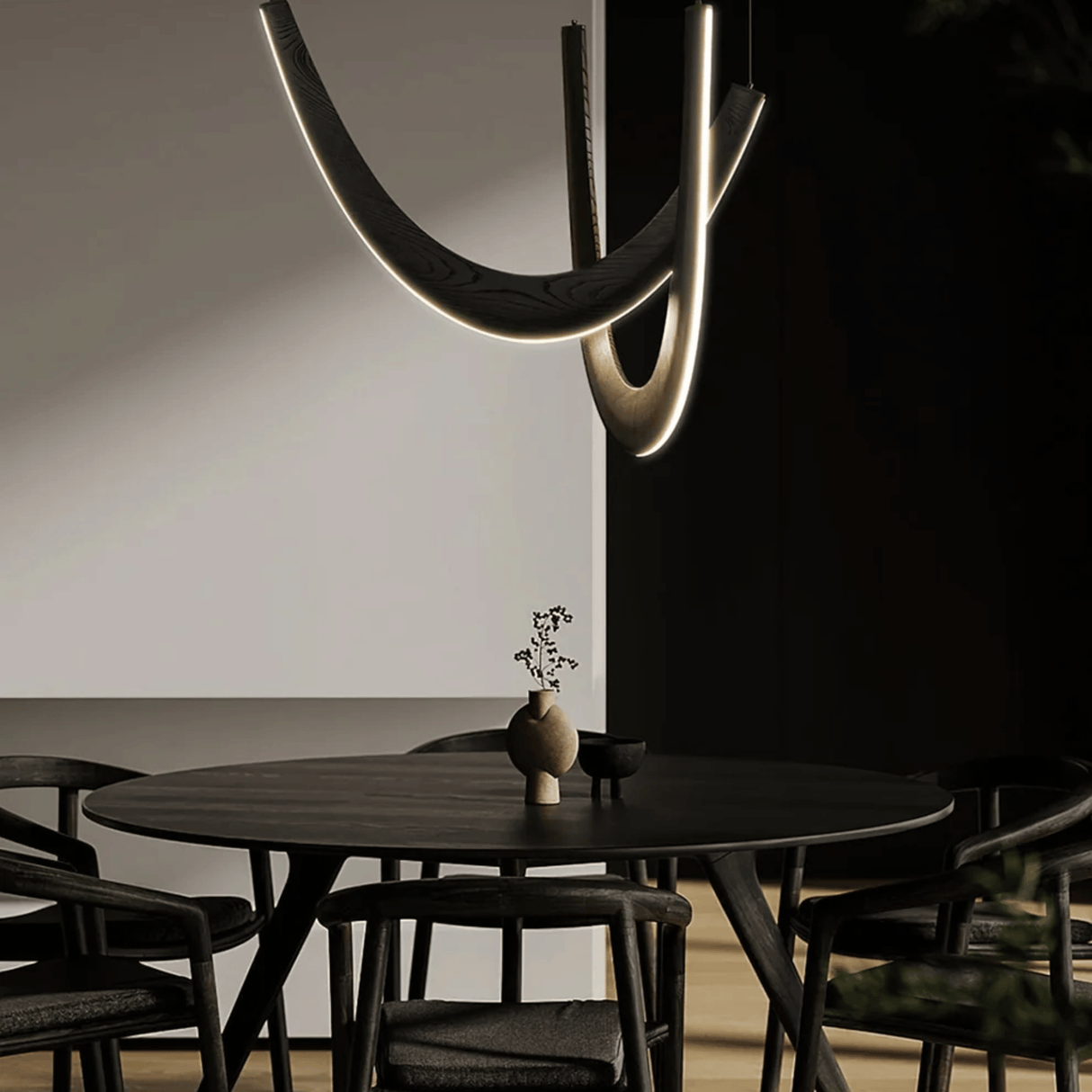 Modern dining room with a black round table and chairs, featuring a unique ceiling light fixture.