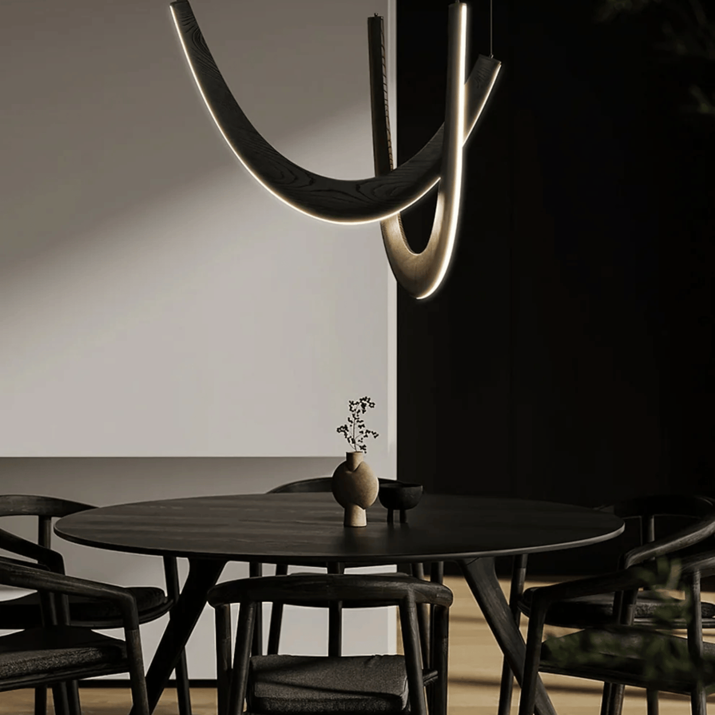 Modern dining room with a black round table and chairs, featuring a unique ceiling light fixture.