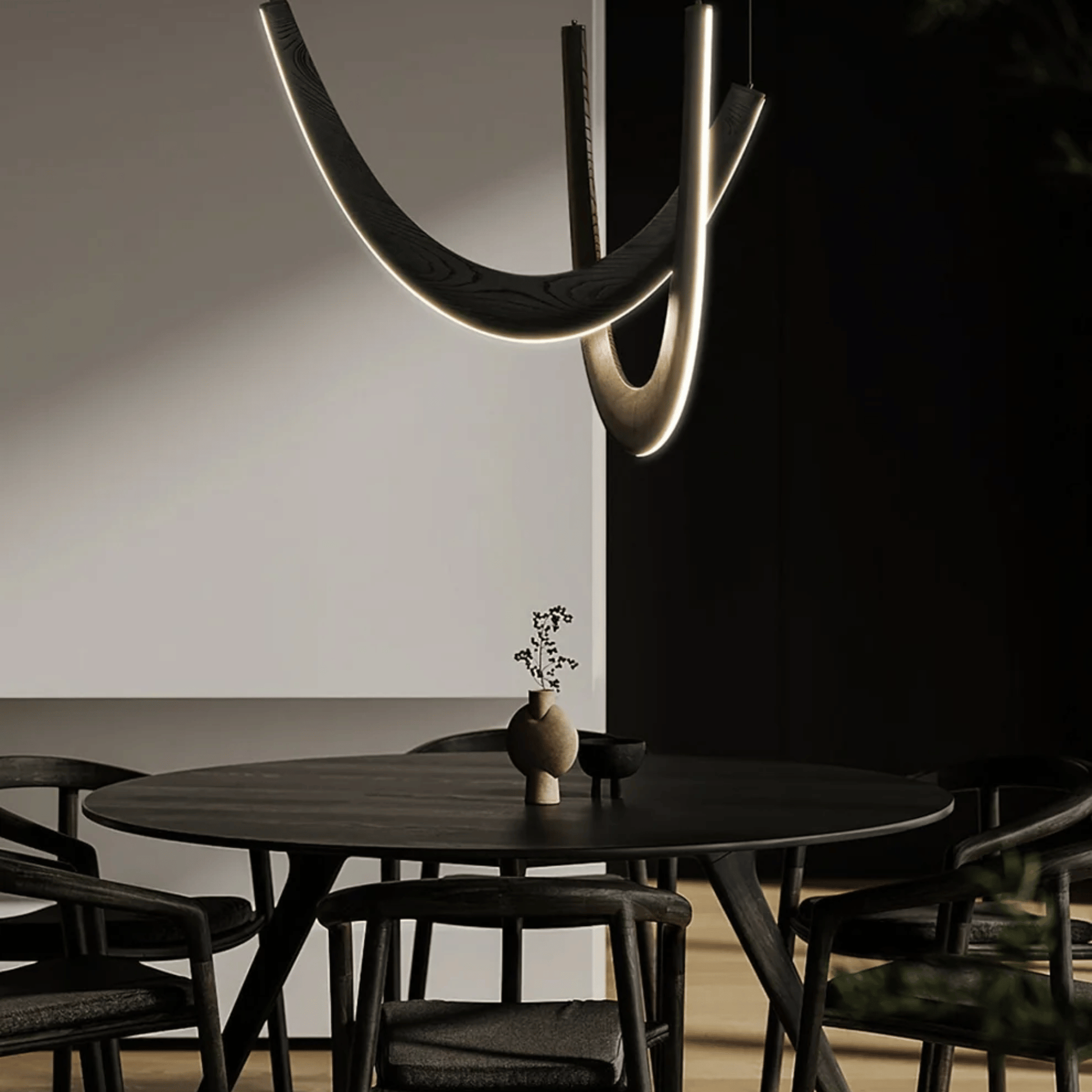 Modern dining room with a black round table and chairs, featuring a unique ceiling light fixture.