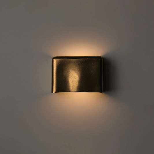 Bronze wall light fixture on a dark gray background