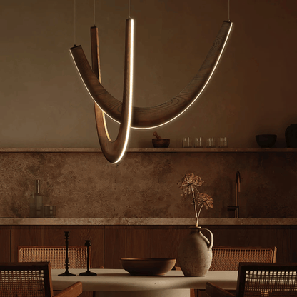 Modern pendant light hanging above a dining table in a dimly lit room.