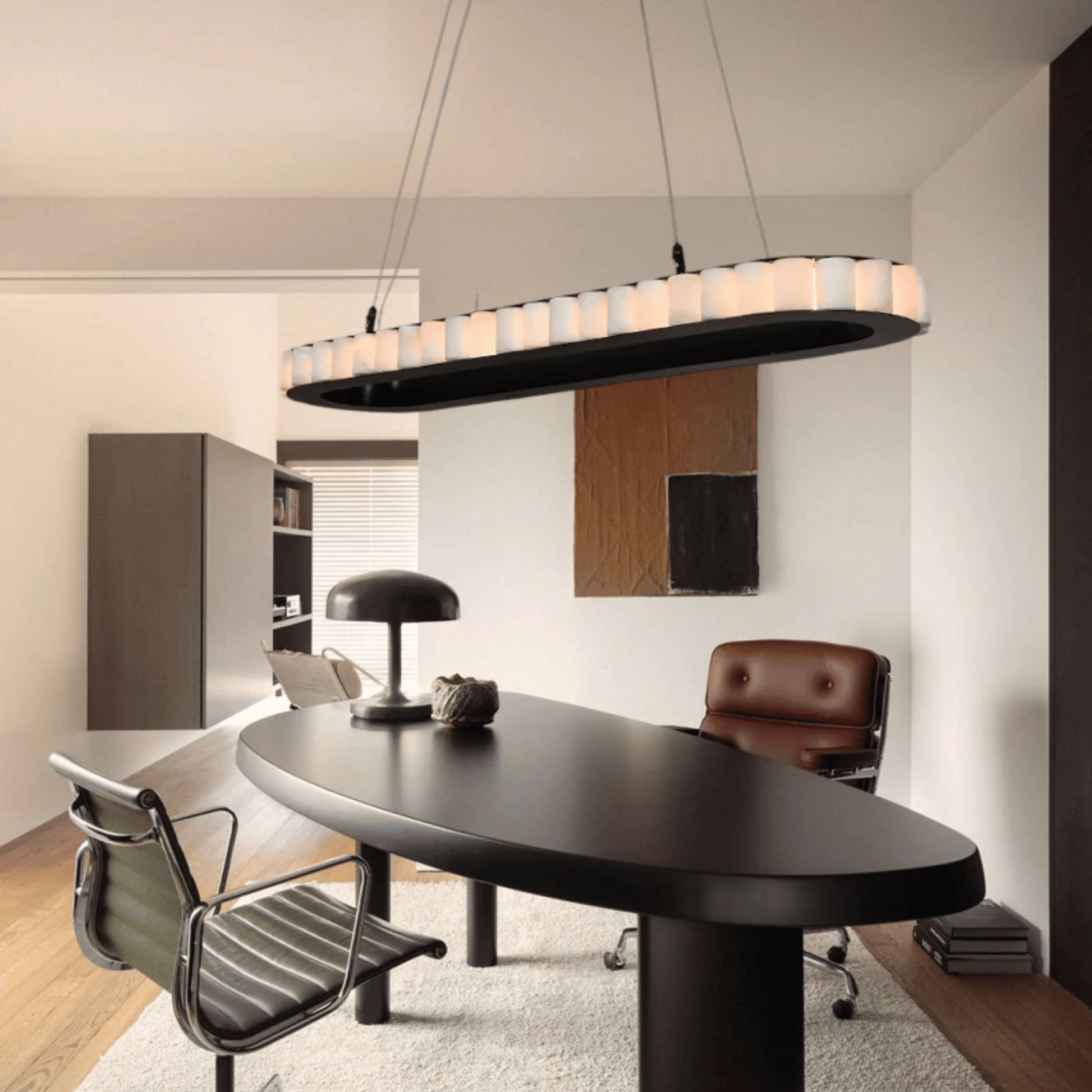 Modern office interior with a black oval desk, chairs, and a stylish pendant light.