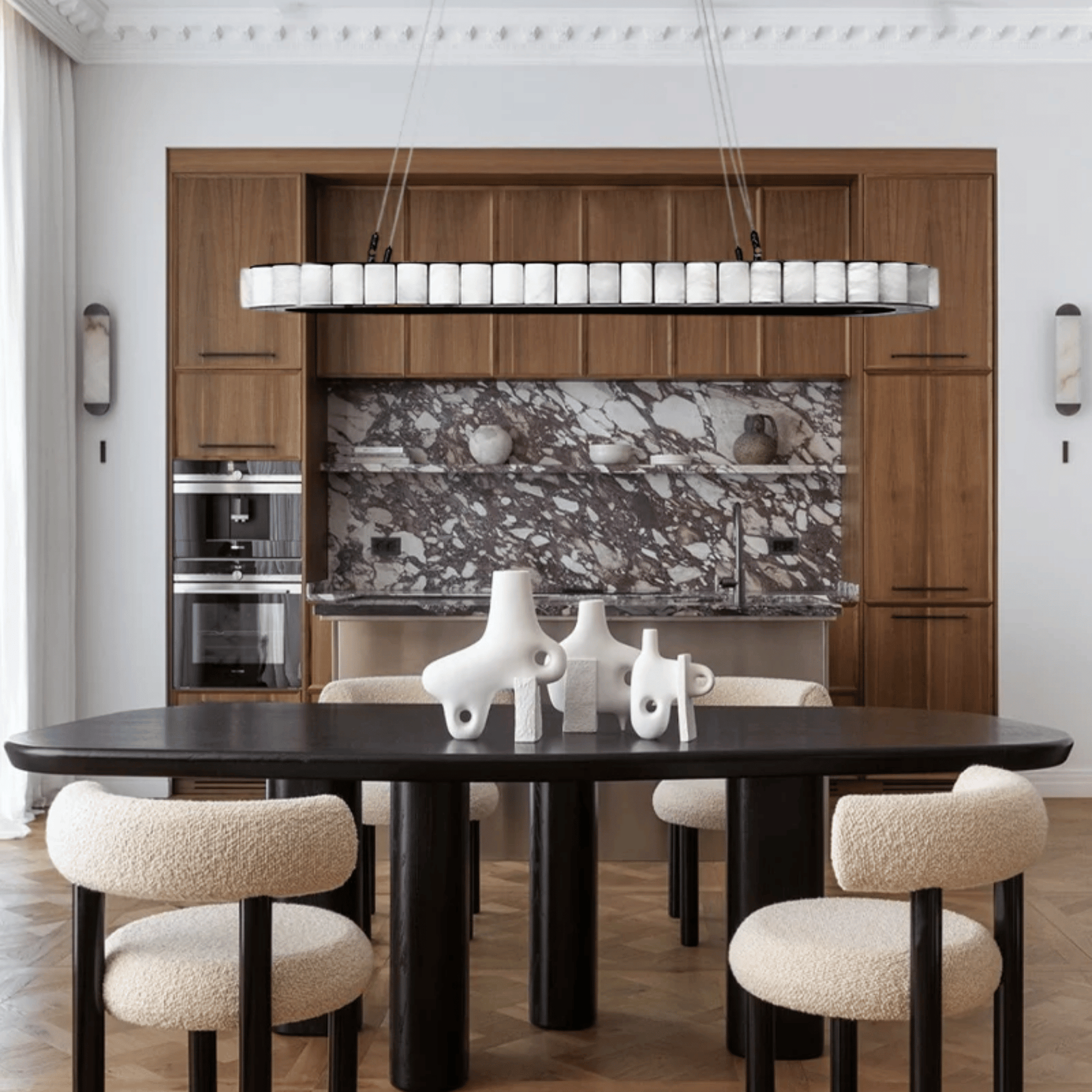 Modern kitchen with wooden cabinets, marble backsplash, and black dining table with beige chairs.