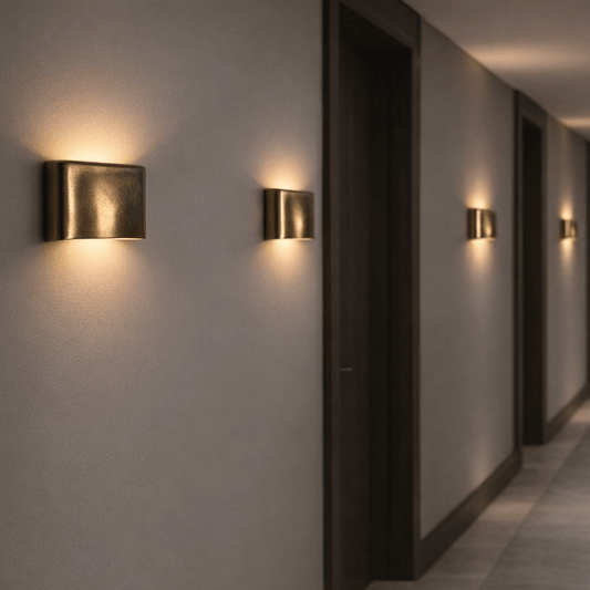 Modern wall lights on a gray wall in a dimly lit hallway.