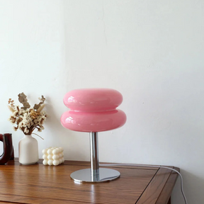 Pink stool on a wooden surface with decorative items against a white wall