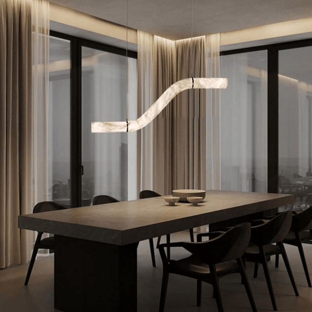 Modern dining room with a long table and chairs, featuring a stylish pendant light.