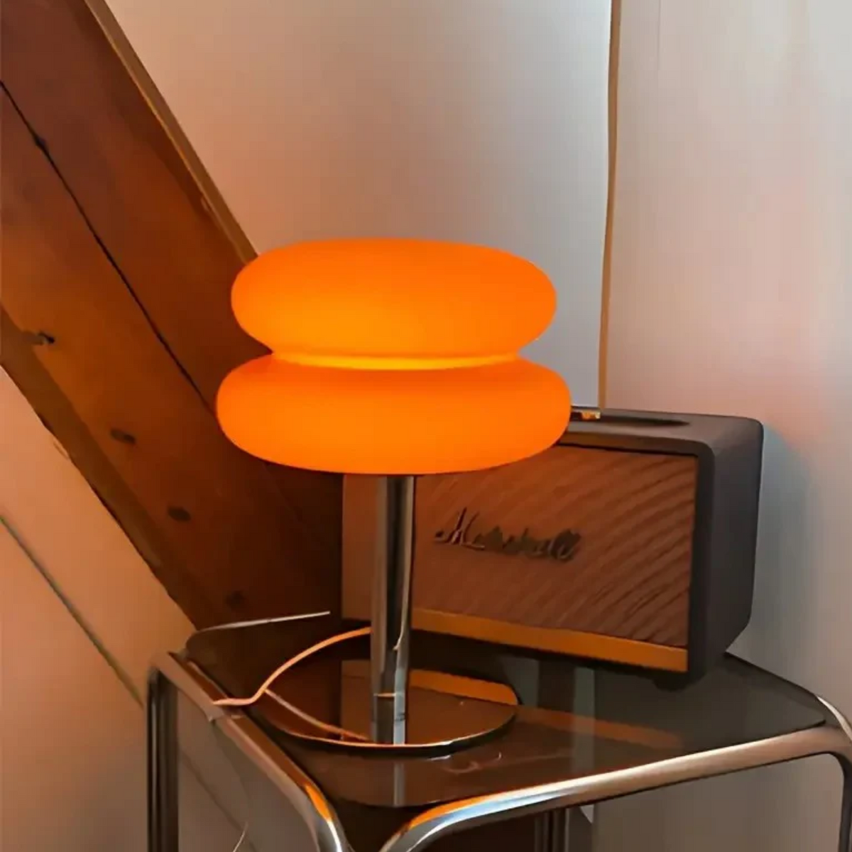 Orange lamp on a glass table next to a Marshall amplifier.