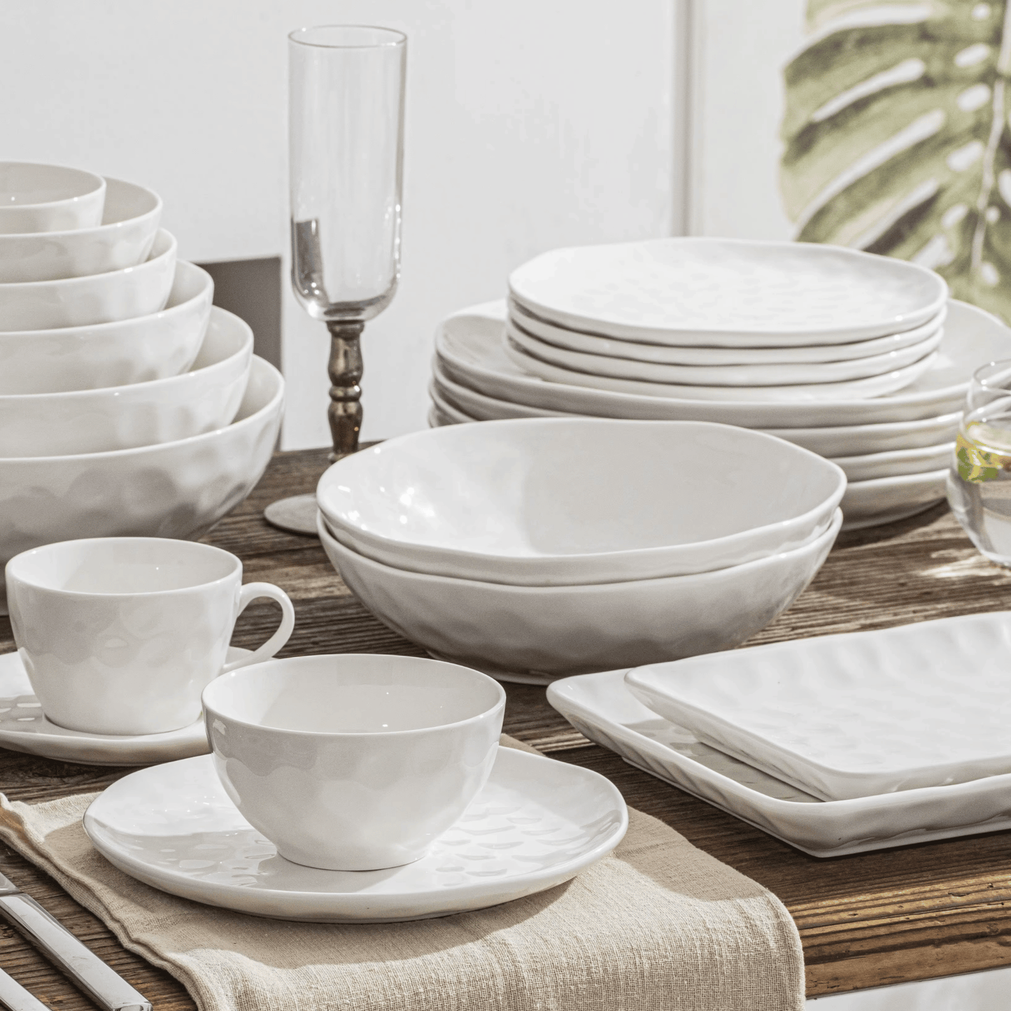 White ceramic dinnerware set on a wooden table with a neutral background