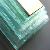 Turquoise glass block with a gold border on a dark background