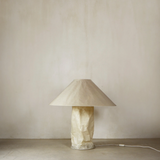 Beige lamp with a textured base on a plain beige background