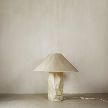 Beige lamp with a textured base on a plain beige background