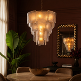 Chandelier hanging above a dining table with a plant and mirror in the background