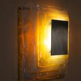 Rectangular light fixture with a black center on a wall.