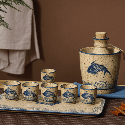 Ceramic sake set with fish design on a tray against a brown background