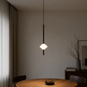Modern pendant light hanging above a wooden table in a minimalistic room.