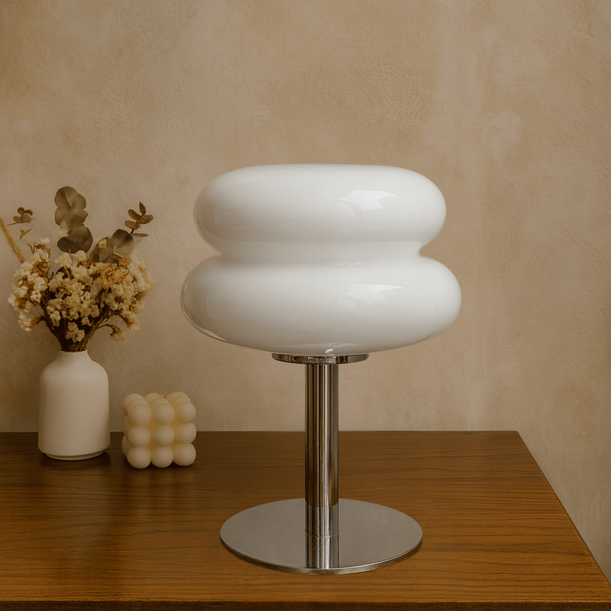 Modern white stool with a metallic base on a wooden surface against a beige wall.