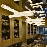 Modern chandelier in a bar setting with shelves and decor.