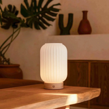 White textured table lamp on a wooden surface with a blurred indoor background
